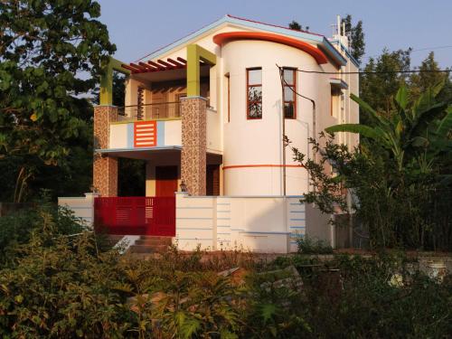 una casa con una puerta roja delante de ella en The Last Villa, en Yercaud