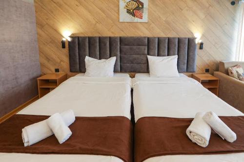 two beds in a hotel room with towels at Family Hotel Gotse Delchev in Gotse Delchev