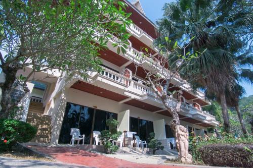 a building with palm trees in front of it at Garden Home Kata in Kata Beach