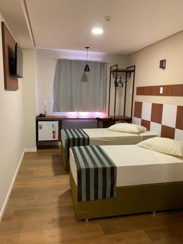 a bedroom with two beds and a television in it at HOTEL MAESTRO EXECUTIVE PATO BRANCO in Pato Branco