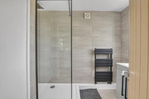 een douche met een glazen deur in een badkamer bij Cozy 2 Bedroom Cottage in West Woodburn