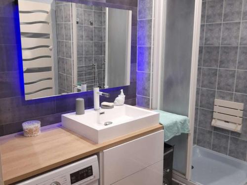 une salle de bain avec un lavabo blanc et un miroir dans l'établissement Appartement T2 à 300m du marché - Balcon, cuisine équipée, chambre confort, idéal vacances. - FR-1-494-183, à Royan