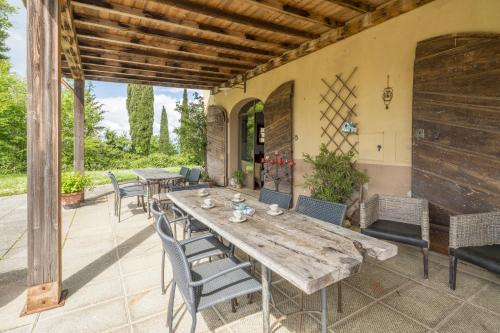 Un patio al aire libre con una mesa y sillas de madera. en San Paolo Farm, Wifi, Pool, Val Di Cecina, en Montecastelli