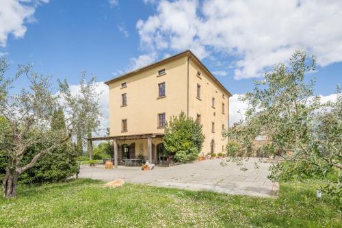 un gran edificio amarillo con árboles delante de él en San Paolo Farm, Wifi, Pool, Val Di Cecina, en Montecastelli