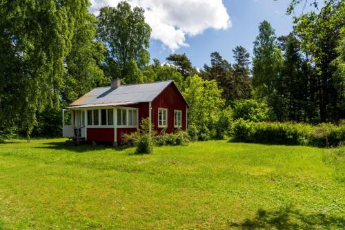 a red barn in a field with trees and grass at Enkel stuga på Fårö, Sudersand in Fårö