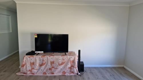 Un televisor de pantalla plana sobre una mesa. en Modern home with Private ensuite, en North Wagga