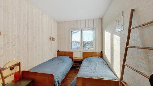 une petite chambre avec deux lits et une fenêtre dans l'établissement V-Sable d'or 01-Vieux Boucau Appartement 3 pièces proche de l'océan, à Vieux-Boucau-les-Bains