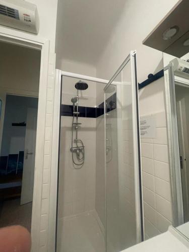 une douche avec une porte vitrée dans une salle de bain dans l'établissement Welcome in the cozy blue nest pedestrian Menton, à Menton