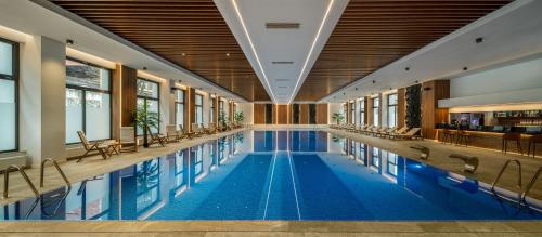 a swimming pool in a hotel with chairs and windows at Hotel Alexandrion Experience in Sinaia