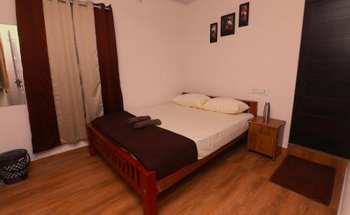 a small bedroom with a bed and a wooden floor at Third Eye Homestay in Cochin
