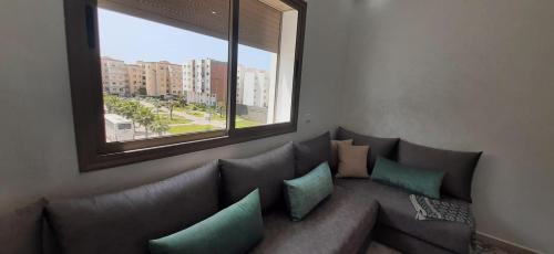 a living room with a couch with pillows and a window at Appartement lumineux près de la plage de Sidi Bouzid in El Jadida