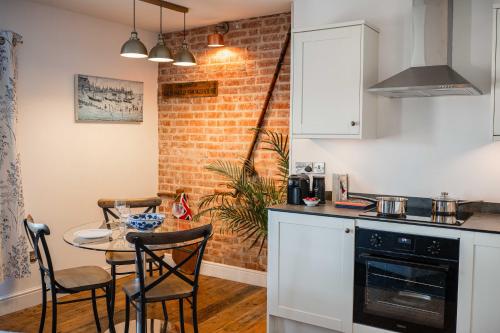 a kitchen with a table and a brick wall at Bramley House Apartment in Southwold