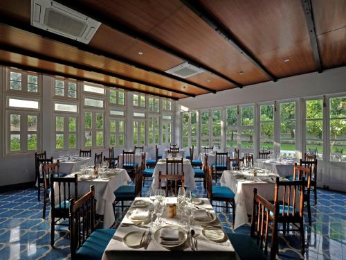 a dining room with tables and chairs and windows at Saraca Hotel Lucknow in Lucknow