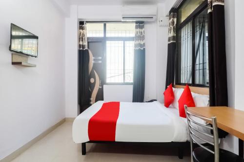 a bedroom with a red and white bed and a table at Hotel O Dream Inn in Patna