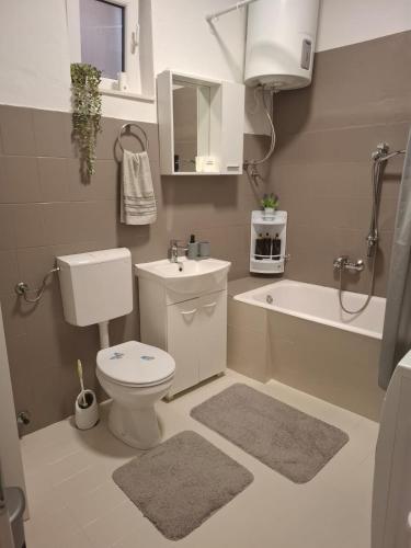 a bathroom with a toilet and a sink and a tub at Apartman Sandra in Podstrana