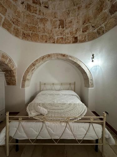 a bed in a room with a stone wall at I Trulli di Mimì in Monopoli