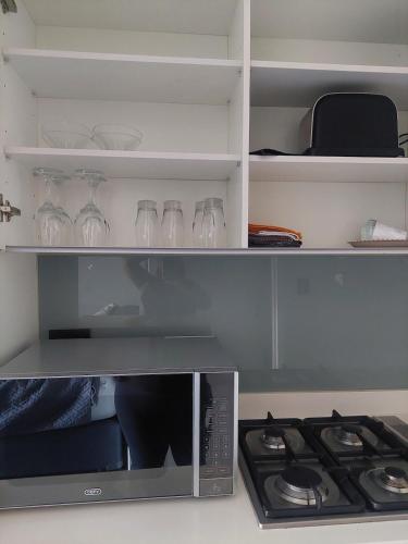 a microwave oven with wine glasses and a stove at Cosy, spacious studio apartment in Umhlanga