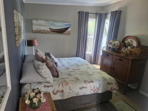 ein Schlafzimmer mit einem Bett, einer Kommode und einem Fenster in der Unterkunft Jamieson Hide Away in Simonʼs Town
