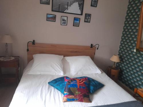 - un lit avec un oreiller et des photos sur le mur dans l'établissement Aux Glycines, à Marcilly-Ogny