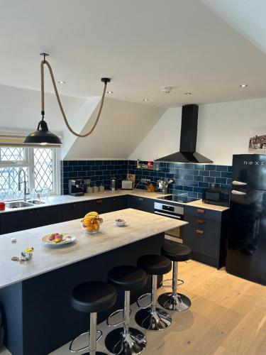 a kitchen with a island with bar stools in it at Modern, centrally located, beach view flat in Pevensey