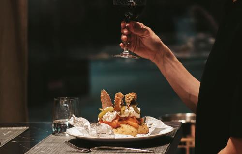 una persona che tiene un bicchiere di vino sopra un piatto di cibo di The Blackpine Hotel - Small Luxury Hotels a Escaldes-Engordany
