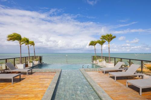 a resort with a swimming pool with palm trees and the ocean at Arpoar Flat 118 - De frente para o mar in João Pessoa