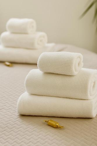 four white towels stacked on top of each other on a bed at Dimore Al Borgo in Montagnana