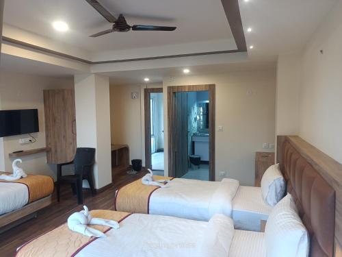a hotel room with two beds and a television at Golden Peaks Hotel & Restaurant in Kalimpong