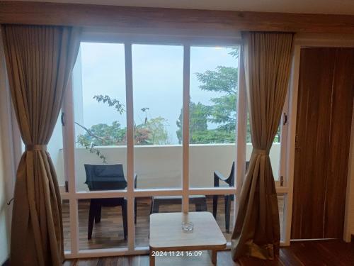 a living room with a large window and a table and chairs at Golden Peaks Hotel & Restaurant in Kalimpong