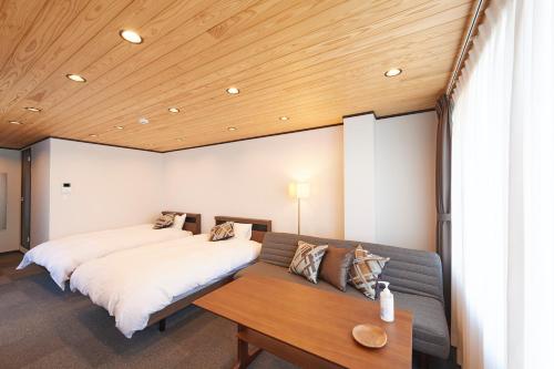 a bedroom with two beds and a couch at OHIO Motosan Shukuba in Takasaki