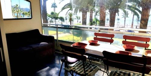 a room with a table and chairs and a large window at Appartement les pieds dans l'eau in Cannes