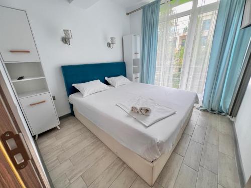 a bedroom with a large white bed with blue curtains at Alezzi Beach Resort - Sea View Suite in Mamaia Nord