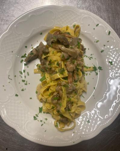 a white plate of pasta with meat and sauce at Castello di Baccaresca in Branca