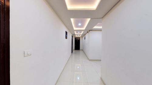 a hallway with white walls and a ceiling with lights at Hotel Eleven Elites in Kota