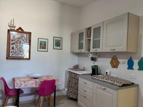Una cocina con encimera y sillas rosas. en Casa vacanza Ligustro appartamento il gabbiano, en SantʼAntìoco