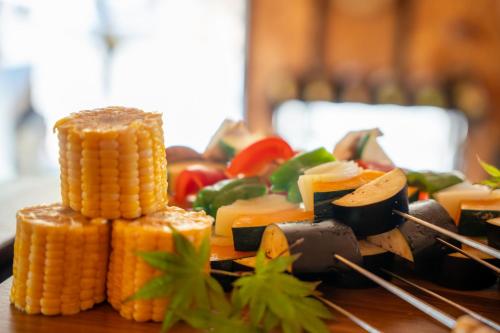 a plate of food with corn on the cob and vegetables at RENEST in Kobe