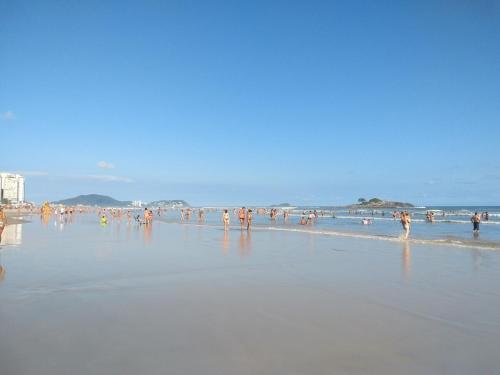 a group of people standing in the water on a beach at Apartamento - kitnet in Guarujá
