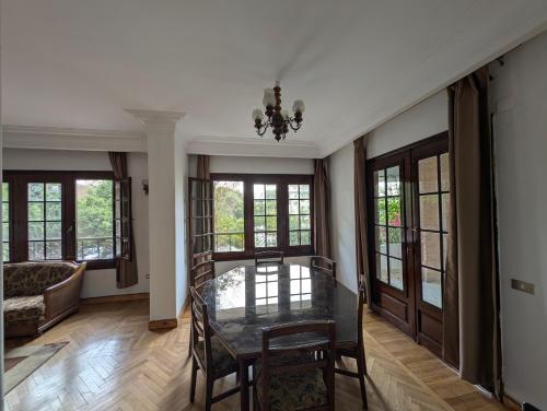 a dining room with a glass table and some windows at Villa Maadi 35 -R 101- Terrace View Room in Cairo
