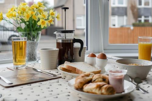 a table with a breakfast of bread and eggs and drinks at Crewe Apartment - Stylish 2 bedroom apt, Garden, Free parking, Edin City in Edinburgh