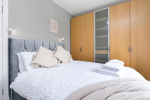 a bedroom with a large white bed with wooden cabinets at Crewe Apartment - Stylish 2 bedroom apt, Garden, Free parking, Edin City in Edinburgh