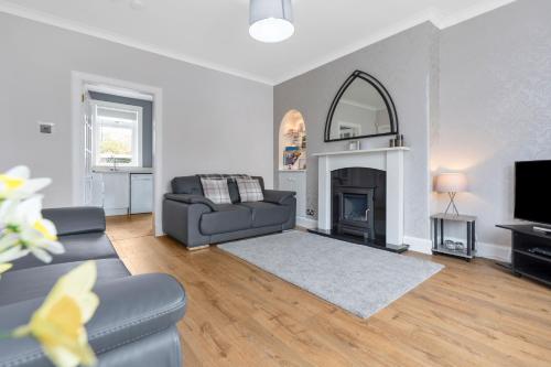 a living room with a couch and a fireplace at Crewe Apartment - Stylish 2 bedroom apt, Garden, Free parking, Edin City in Edinburgh