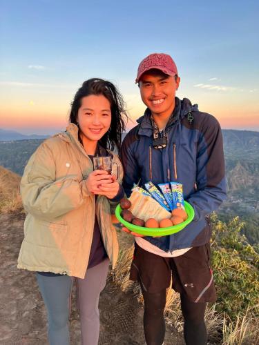 a man and woman standing on top of a mountain at mount batur 2 day sunset and sunsrise in Kintamani