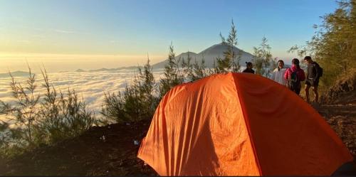 a group of people standing around an orange tent at mount batur 2 day sunset and sunsrise in Kintamani