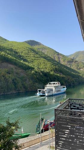 a large boat on a river with a hill at Raja Hotel Fierze in Ndërlisaj