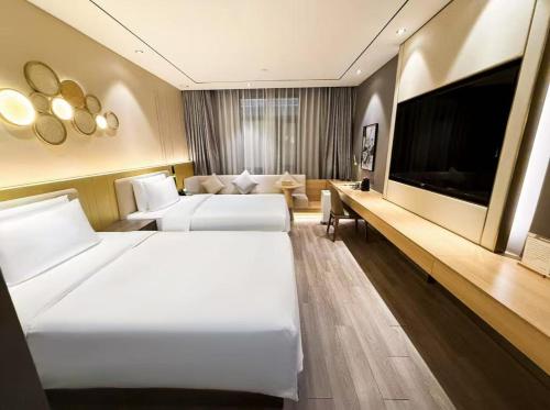 a hotel room with two beds and a flat screen tv at Crystal Orange Hotel Shanghai Hongqiao Hub Railway Station in Shanghai