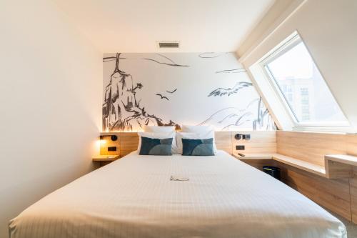 a bedroom with a large bed with a window at GREEN PARK HOTEL PARIS in Paris
