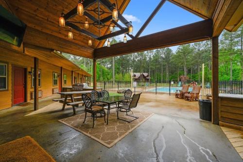 een terras met een tafel en stoelen en een zwembad bij Big Timber Lodge in Broken Bow