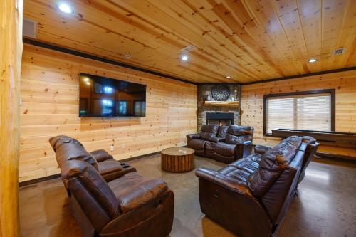 een woonkamer met lederen meubels en een flatscreen-tv bij Big Timber Lodge in Broken Bow
