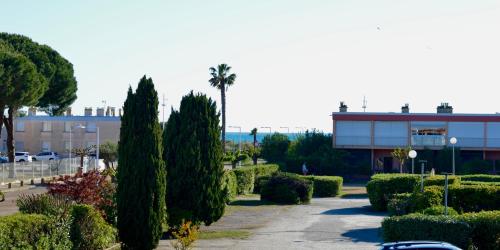 a parking lot with a palm tree and a building at Studio élégant et vue mer au Boucanet in Le Grau-du-Roi