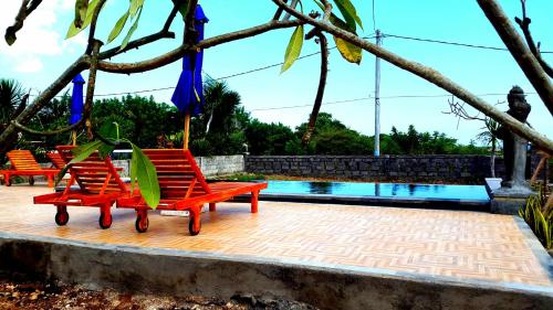 レンボンガン島にあるKubu Sunset Guest Houseのスイミングプールの隣に赤い椅子2脚
